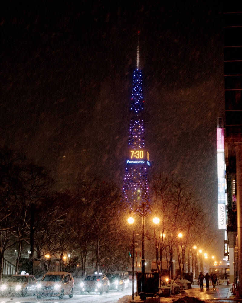 A picture of the Sapporo TV tower at night somewhat obscured by the snow.

